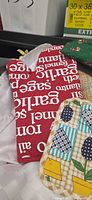 Red text oven mitt, beige dishcloth, partial pot holder visible