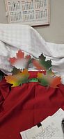 four painted steel maple leaves arranged on red cloth