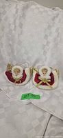 Two red velvet angel ornaments on white cloth