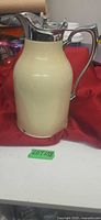 Front view of cream metal vacuum carafe with chrome lid and handle