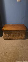 Front view of wicker chest showing woven body and wood lid