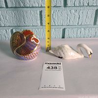 Rooster paperweight and swan figurine side by side with scale