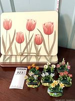 Stack of tulip print placemats with seven porcelain flower place card holders