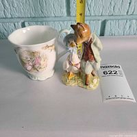 Figurine placed next to matching mug with tape measure for scale