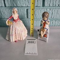 Both figurines side by side with ruler for scale