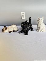 Front view of three porcelain cat figurines