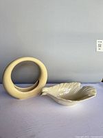 Front view of both ivory pieces: circular vase and shell dove dish
