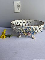Side view showing lattice design, applied flowers, gold rim, four feet