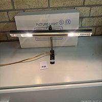 Picture light illuminated on shelf, box visible behind