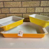 Front view of three yellow Pyrex dishes – rectangular, square, loaf – showing interiors