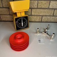 All items together: yellow scale, red egg cups stack, chrome candleholder