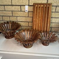 Three wooden fruit bowls and one slatted bread board displayed together