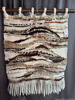 Full view of wool wall hanging with fringe on wood dowel