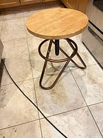 Stool full view side angle showing wood seat and metal base