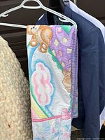 Pastel quilted teddy bear blanket hanging on hanger