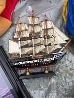 Overall view of wooden sailing ship model with fabric sails and stand