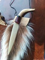 Bone cutter hanging: shows bone blade, antler handle, fur pelt, leather wrap, cord