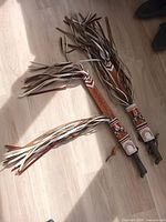 Two machetes inside sheaths showing full length and long leather tassels