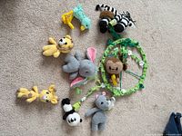 All components of crochet mobile laid on carpet showing ring and eight animal figures