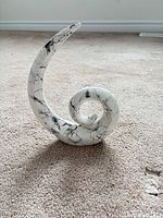 Front view of white ceramic spiral sculpture with black marbling