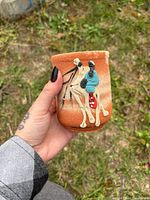 Oblique view of cup exterior showing raised painted rider and animal motif