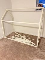 Full view of disassembled white house-shape bed frame and slats