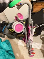 Stroller folded showing gray frame, pink wheels, patterned fabric seat
