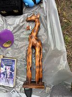 Full view of carved wooden giraffe with detached ear lying beside it