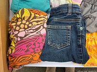 Folded girls animal-print zip sweater next to blue denim jeans