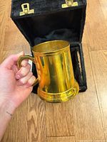 Tankard held in hand beside open black case