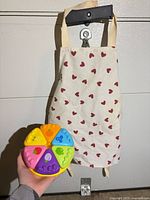 Apron hanging; multicolor pie shape sorter toy held in hand