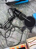 USB condenser microphone, scissor-arm stand, windscreen, detached pop filter visible on surface