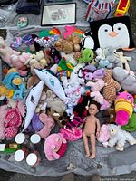 Overview of entire lot showing stuffed animals, American Girl doll, fidget toys, penguin pillow, jars, frames