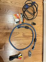 All items laid out on floor: VGA cable, HDMI cable, AV cable, earbuds, USB adapter, Energizer 9V battery