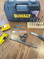 Group shot of all items including DeWalt case, battery, Stanley stud finder, measuring tools, spade bits, sharpener