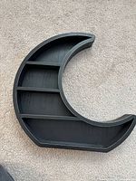 Black crescent moon shelf on carpet showing overall shape and shelves