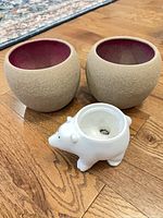 Two beige textured planters and white polar bear planter on wood floor