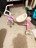 Side view of pink Disney Princess tricycle showing frame, seat, handlebars, and wheels