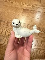 Front view of white ceramic seal figurine in hand