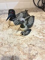 Three carved wooden loons displayed on countertop