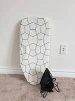 Ironing board with geometric cover and iron at base