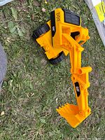 Full view of yellow and black CAT toy excavator on grass