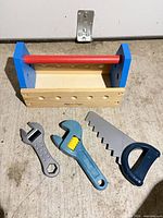 Overall view of wooden toolbox and three plastic toy tools