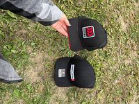 Two black logo snapback caps on ground