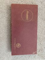 Closed maroon Scrabble box top with gold logo and manufacturer mark