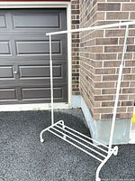 Full frontal view of white rolling garment rack showing main structure