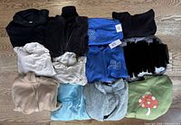 Overview of twelve XS garments and sweatpants arranged on floor