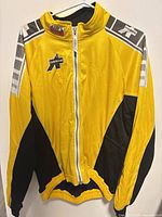 Front view of yellow Assos cycling windbreaker jacket hanging on hanger