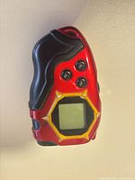 Front of red/black/gold Digimon D-Tector Digivice showing LCD screen and buttons