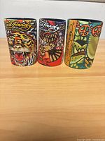 Front view of all three Ed Hardy can koozies showing tiger, eagle and bulldog artwork